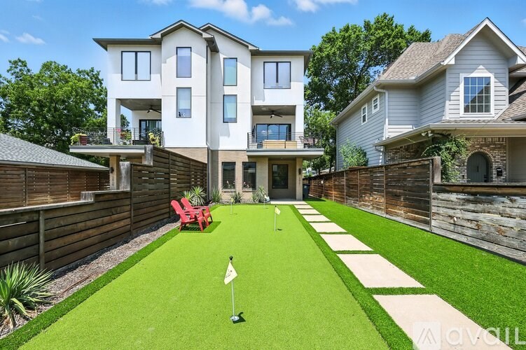 A house with a green lawn and a white flag on a golf hole.
