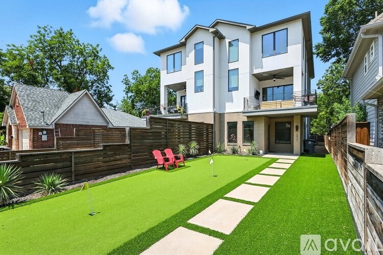 A modern house with a well-manicured lawn and a red chair.