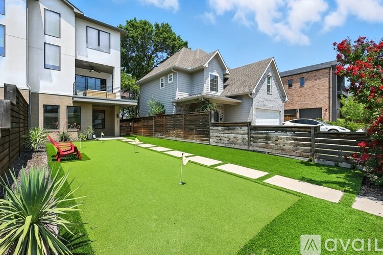 A backyard with a putting green and a white fence.