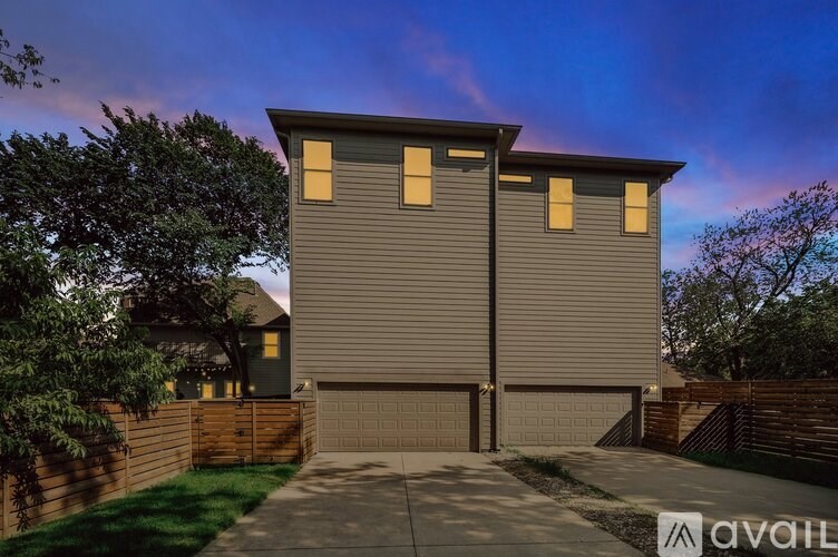 A modern house with a grey facade and a brown fence.
