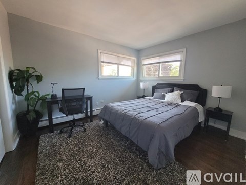A bedroom with a bed, a desk with a chair, and a potted plant.