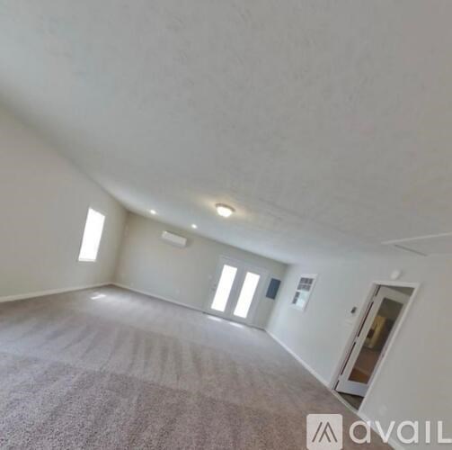 A spacious room with a carpeted floor and a door on the right side.