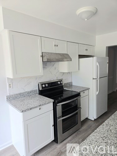 A room with a wooden floor, a white door, and a window with curtains.