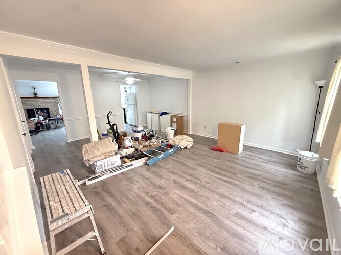 A room with wooden flooring and white walls is being renovated.