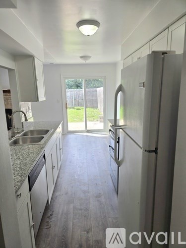 A white washing machine in a small, white-walled laundry room.