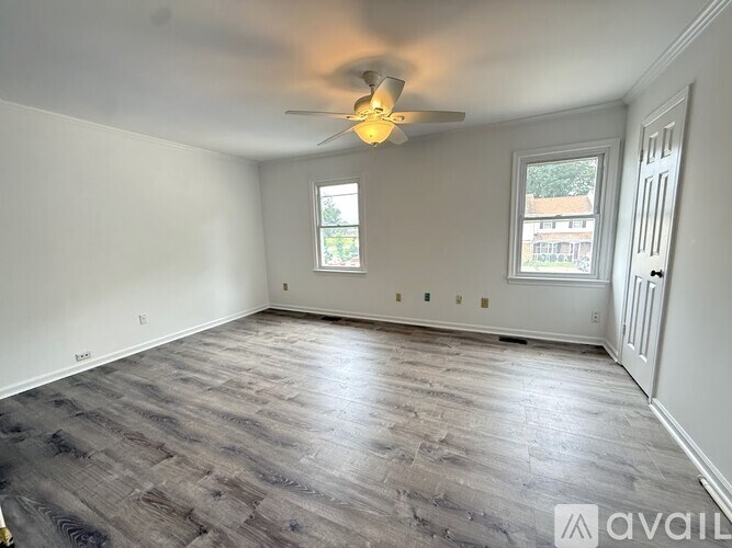 A room with a ceiling fan and two windows.