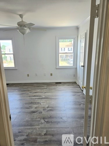 A room with a ceiling fan and wooden flooring.