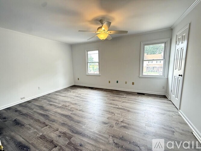 A white tiled shower with a drain in the middle.