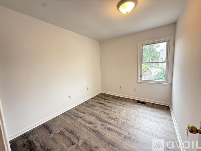 A room with a window and a wooden floor.