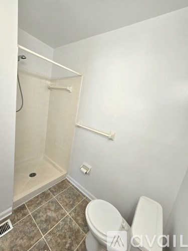 A white toilet in a small bathroom with a walk-in shower.