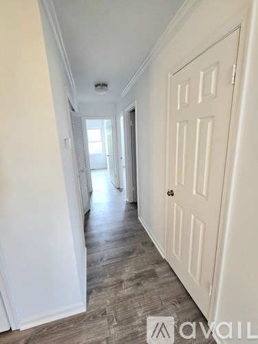 A hallway with a white door and wooden flooring.