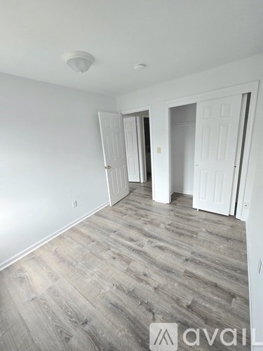 A room with white walls and wood flooring with two doors.