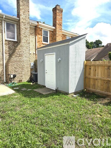 A shed sits in a yard next to a house.