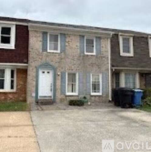 A house with a grey front door and a blue trash bin.