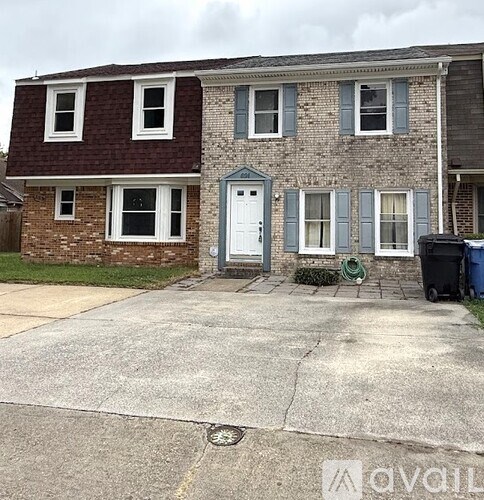 A two-story house with a white door and a small front yard.