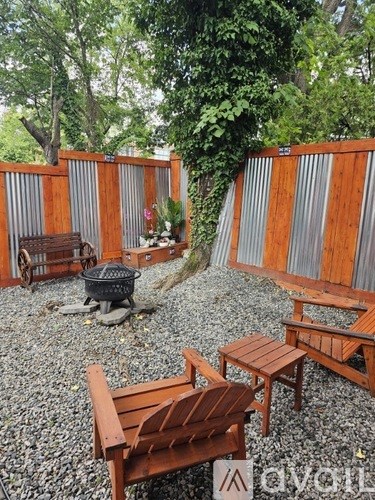 A backyard with a fire pit and wooden furniture.