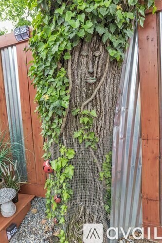 A tree with a face carved into it is surrounded by greenery.
