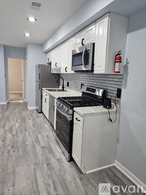 A kitchen with white cabinets and a grey floor.