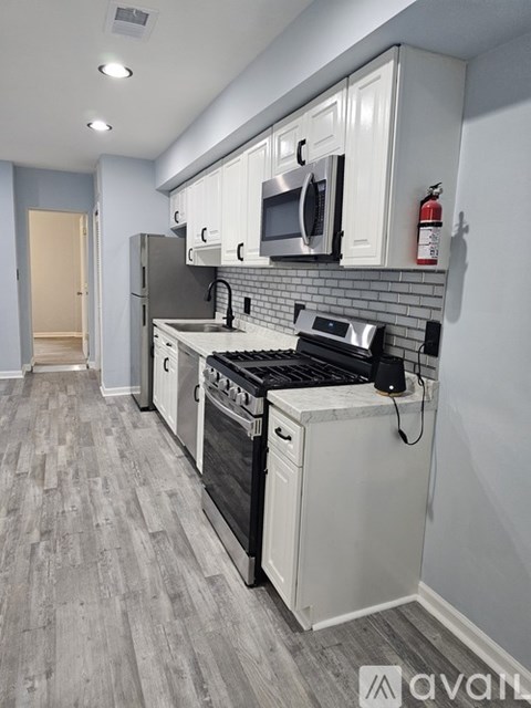 A kitchen with white cabinets and a grey floor.