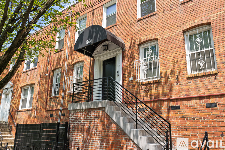 A brick building with a black awning and a staircase leading to the entrance.