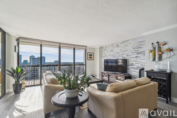A living room with a couch, a table, and a balcony with a view of the city.
