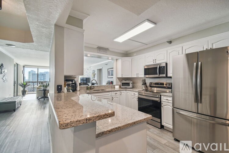 A modern kitchen with stainless steel appliances and a marble countertop.
