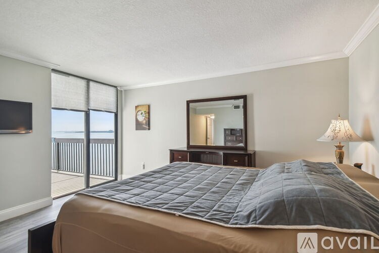 A bedroom with a large bed and a balcony.