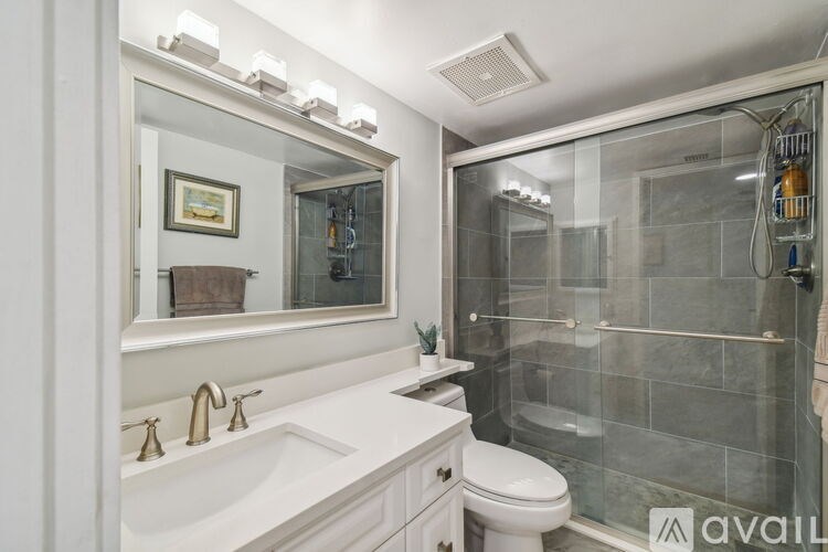 A bathroom with a white sink and a glass shower stall.
