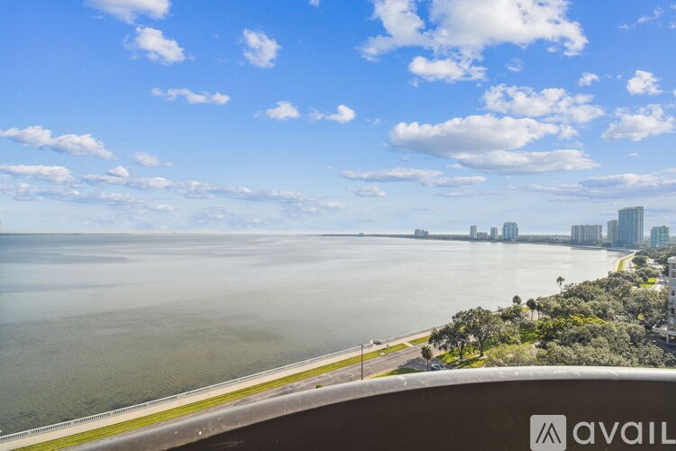 A view of a beach with buildings in the distance and a clear sky.