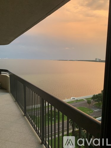 A balcony overlooks a body of water with a sunset in the distance.