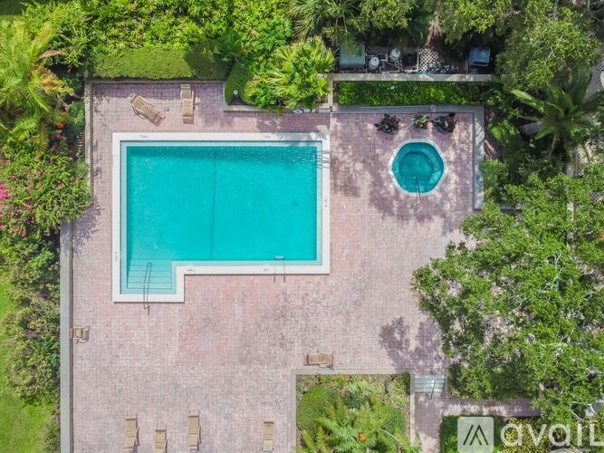 An aerial view of a swimming pool surrounded by a brick wall and greenery.