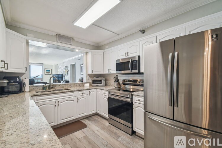 A kitchen with a stainless steel refrigerator and white cabinets.