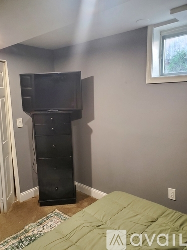 A bedroom with a bed, a dresser, and a television.