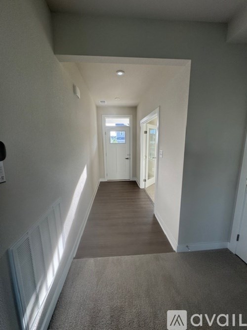 A hallway with a carpeted floor and white walls.
