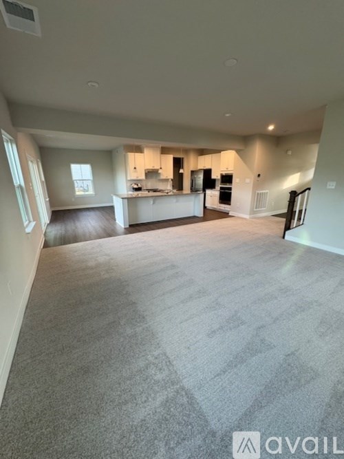 A spacious living room with a kitchen in the background.