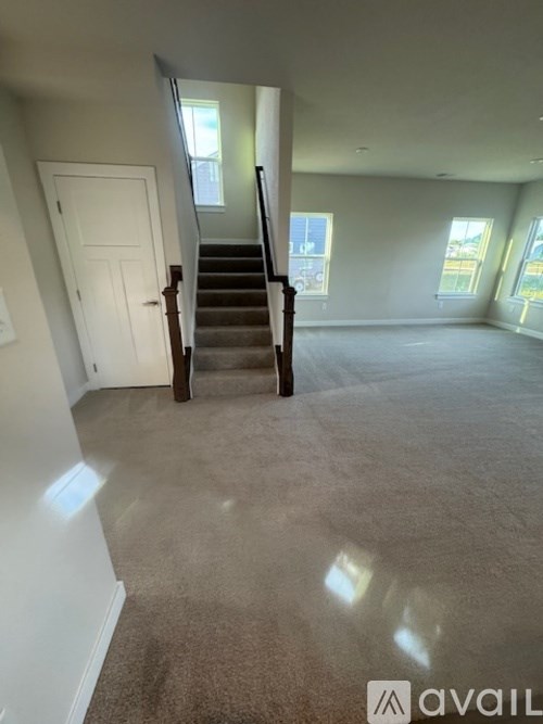 A carpeted room with a staircase leading to another room.