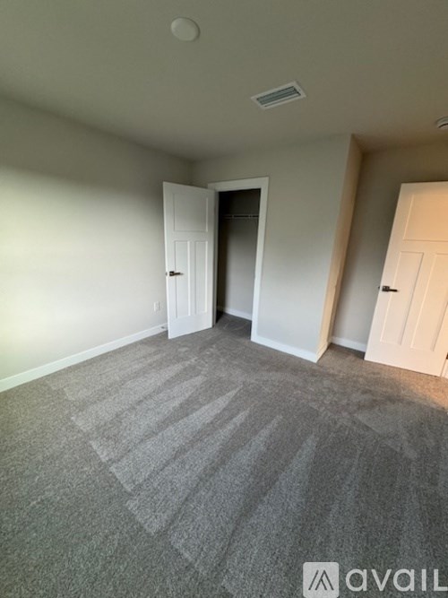 A room with grey carpet and two white doors.