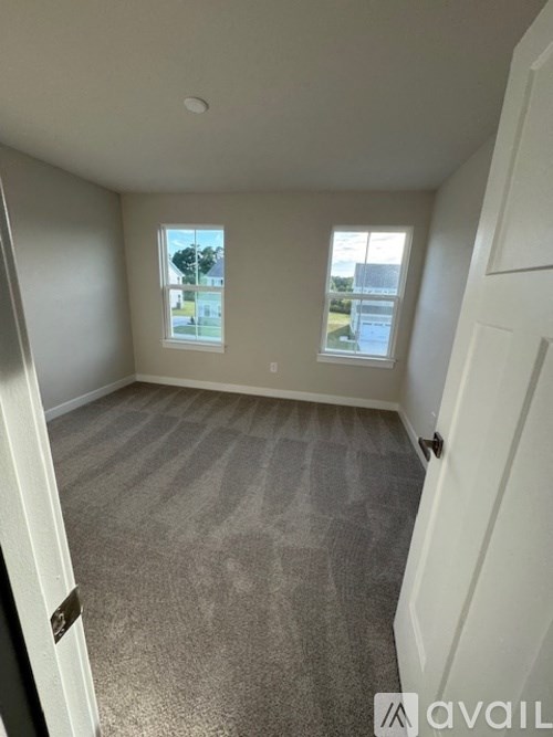 A room with carpeted floor and two windows.