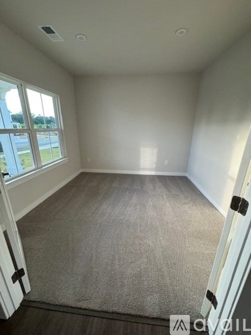 A room with a carpeted floor and a window overlooking a street.