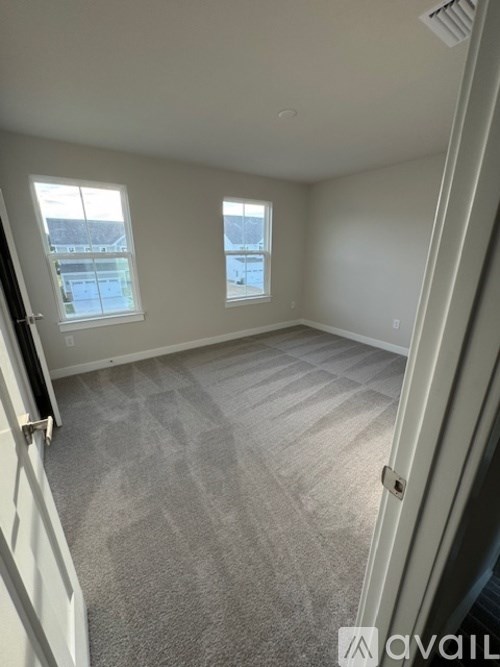 A room with a carpeted floor and two windows.