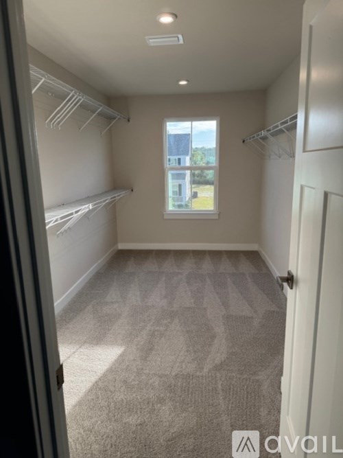 A room with a carpeted floor and a window showing an outdoor view.
