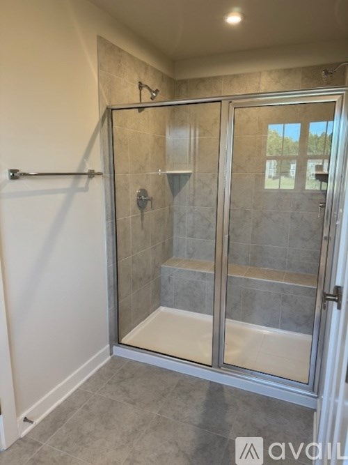 A shower with a glass door and a tiled wall.