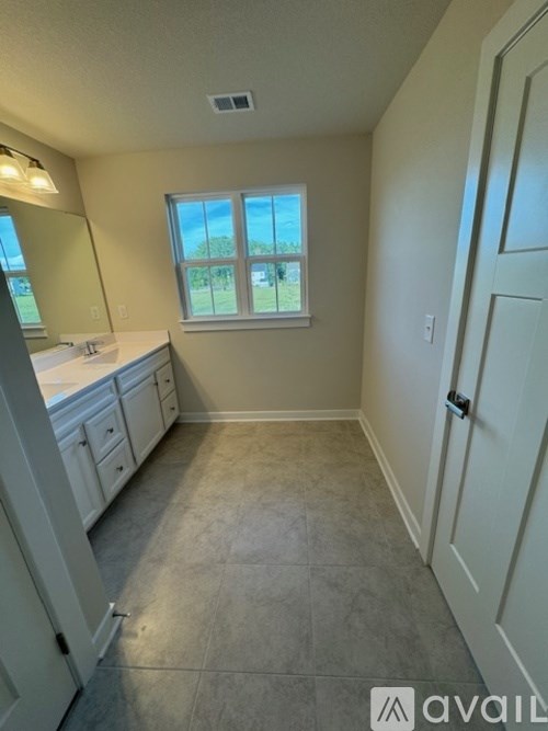 A bathroom with a window, sink, and cabinets.