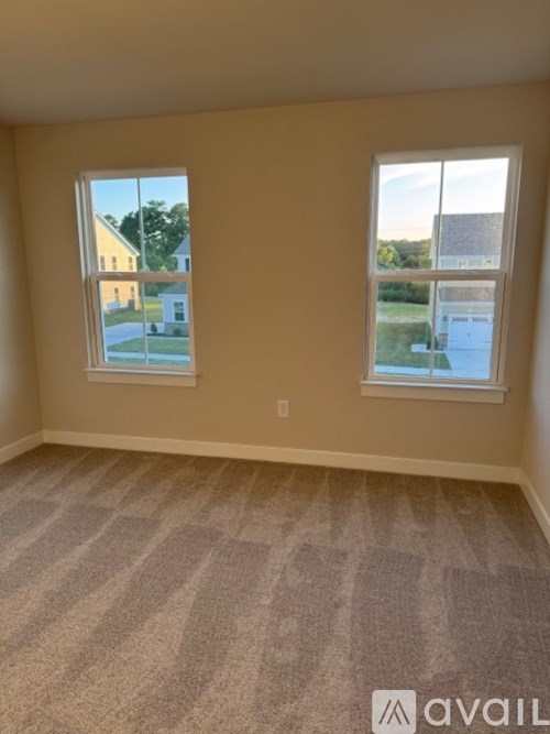 A room with two windows and carpeted flooring.