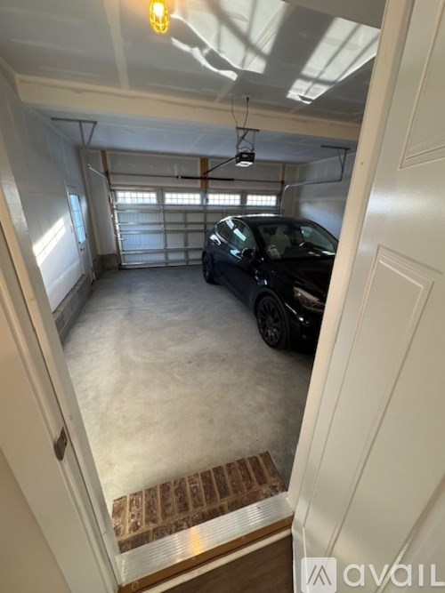 A black car is parked in a garage with a white door.