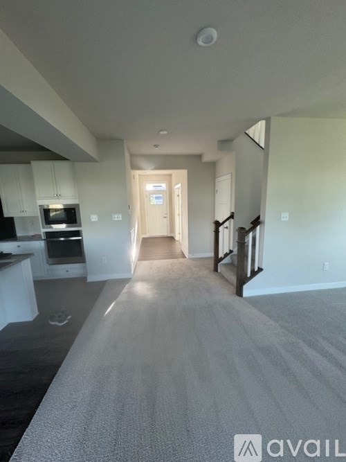 A spacious hallway with a carpeted floor leads to a door.