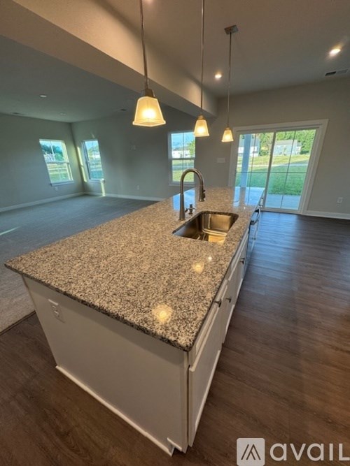 A kitchen with granite countertops and pendant lights.