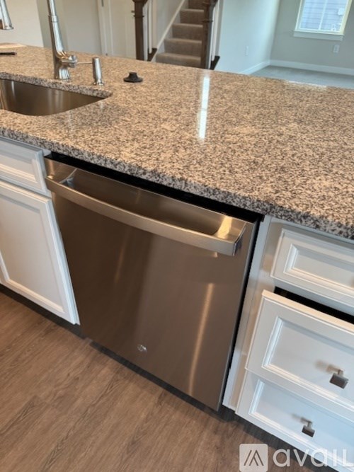 A kitchen with a granite countertop and stainless steel dishwasher.