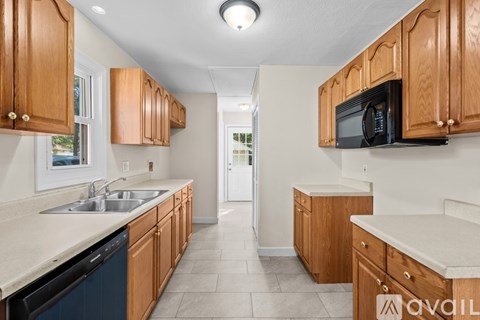 A kitchen with wooden cabinets and a black microwave.