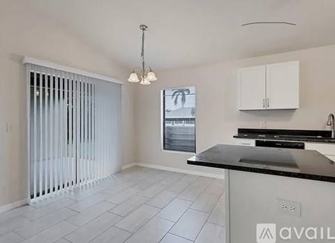 A kitchen with white cabinets and a black countertop.